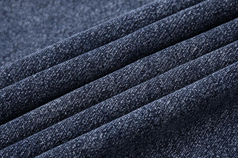 Close-up of acid-wash fabric drape on sweatshirt, textured blue-gray weave